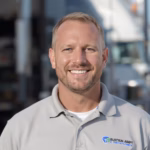 Portrait of freight driver Jordan Williams smiling in front of a semi-truck.